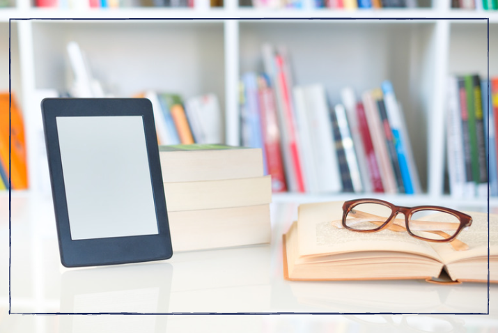 Eine Brille auf einem offenen Buch und ein E-Book.
