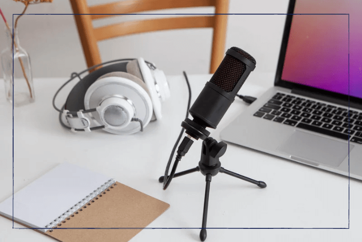 Kostenlos Werbung machen: Ein Mikrofon und Kopfhörer stehen mit einem Laptop auf einem Schreibtisch.